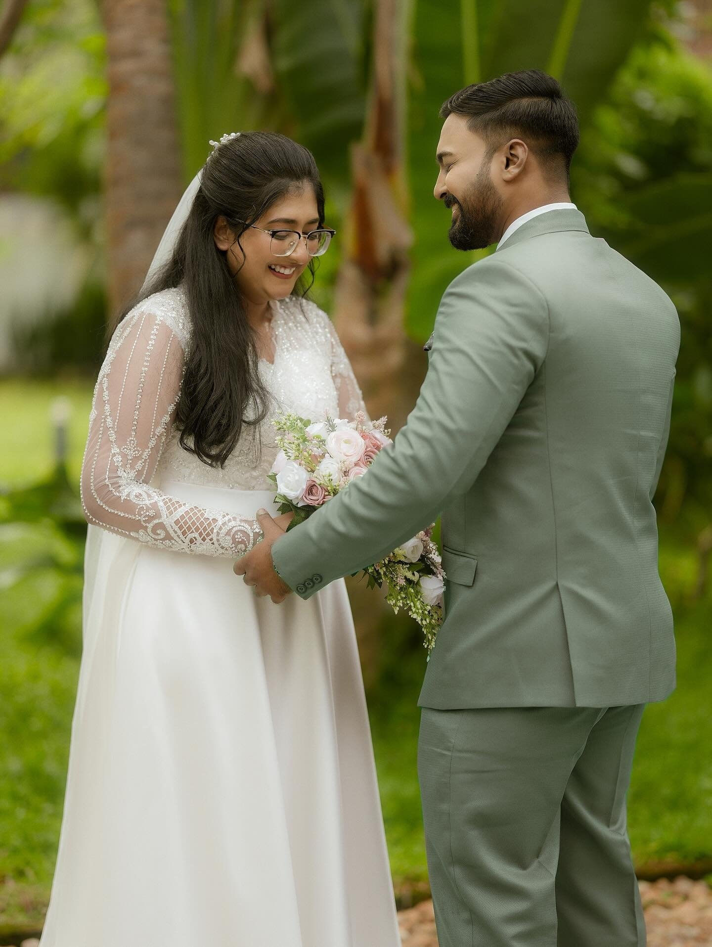 A bride and groom standing together beside their wedding car