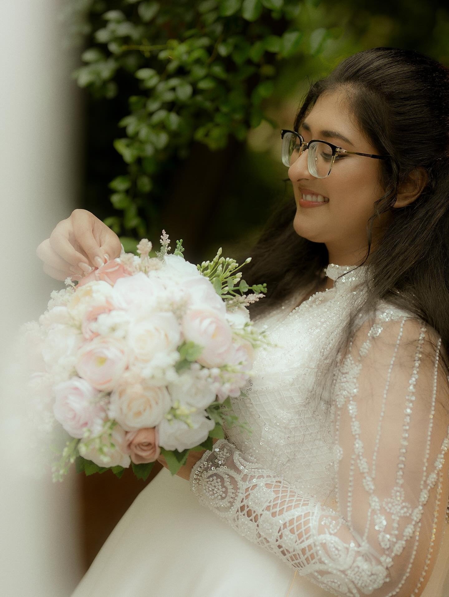 A bride arranging flowers in her pastel wedding bouquet
